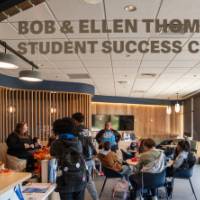 Photo from outside new space showing "Bob & Ellen Thompson Student Success Center" lettering on window and people in side